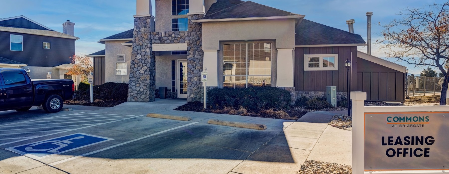 a leasing office with a sign and a parking lot